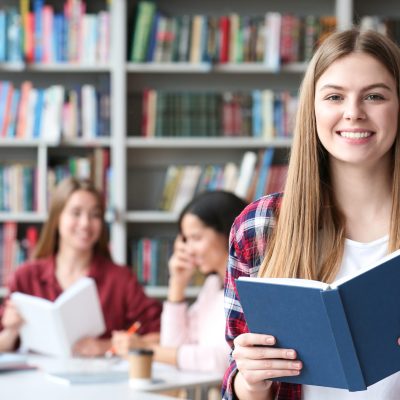 Young student with book in library, space for text. Banner design