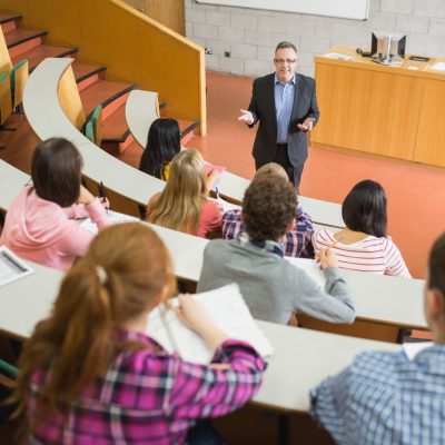 Elegant teacher with students sitting at the college lecture hall